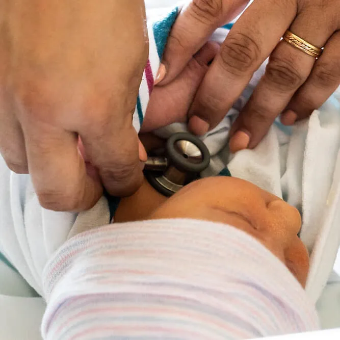 Person checking babies heart though a stethoscope