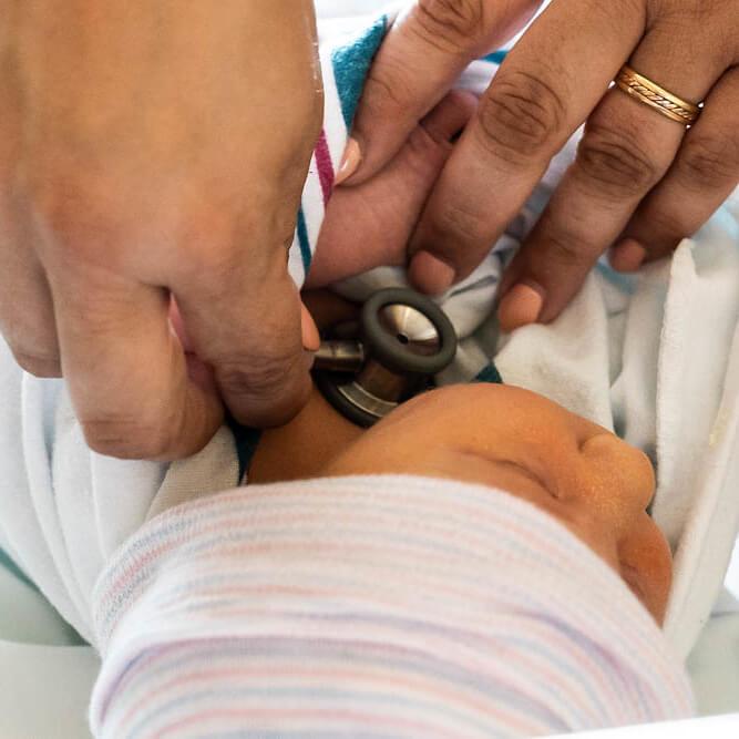 Person checking babies heart though a stethoscope