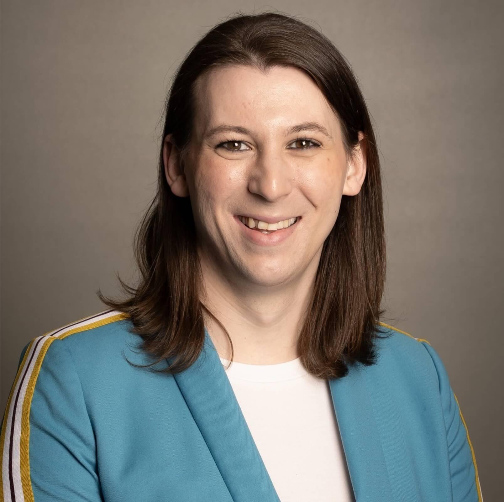 taylor small in a blue blazer over a white shirt with a grey background, in a professional studio