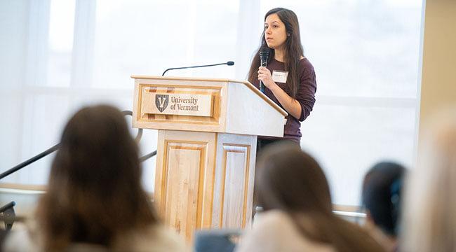 a young Phd students answers questions at the lectern of a conference