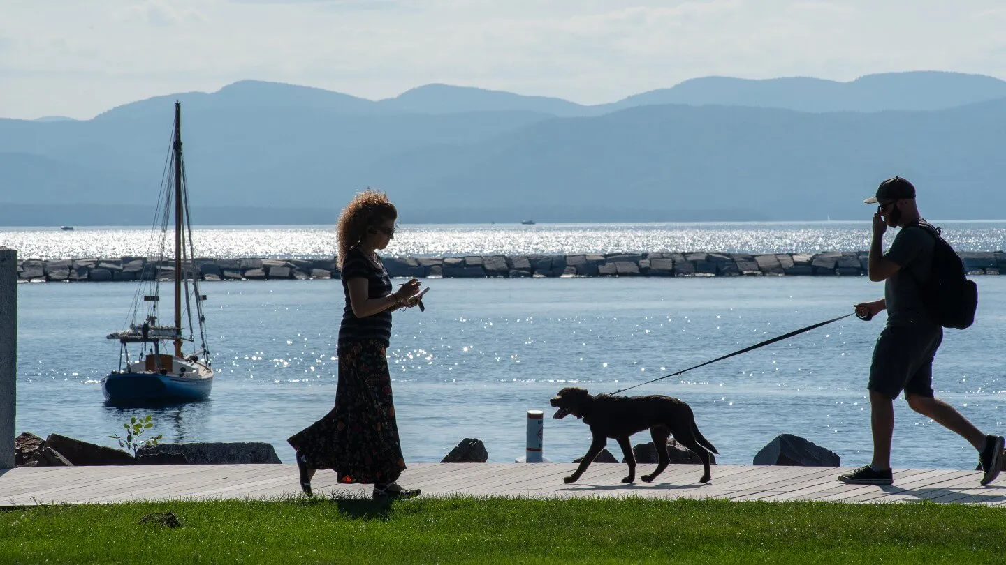 Two people and a dog walking along Burlington waterfront