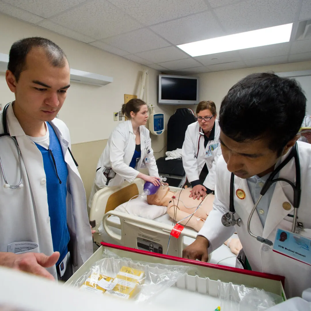 Students practicing a medical simulation on a dummy