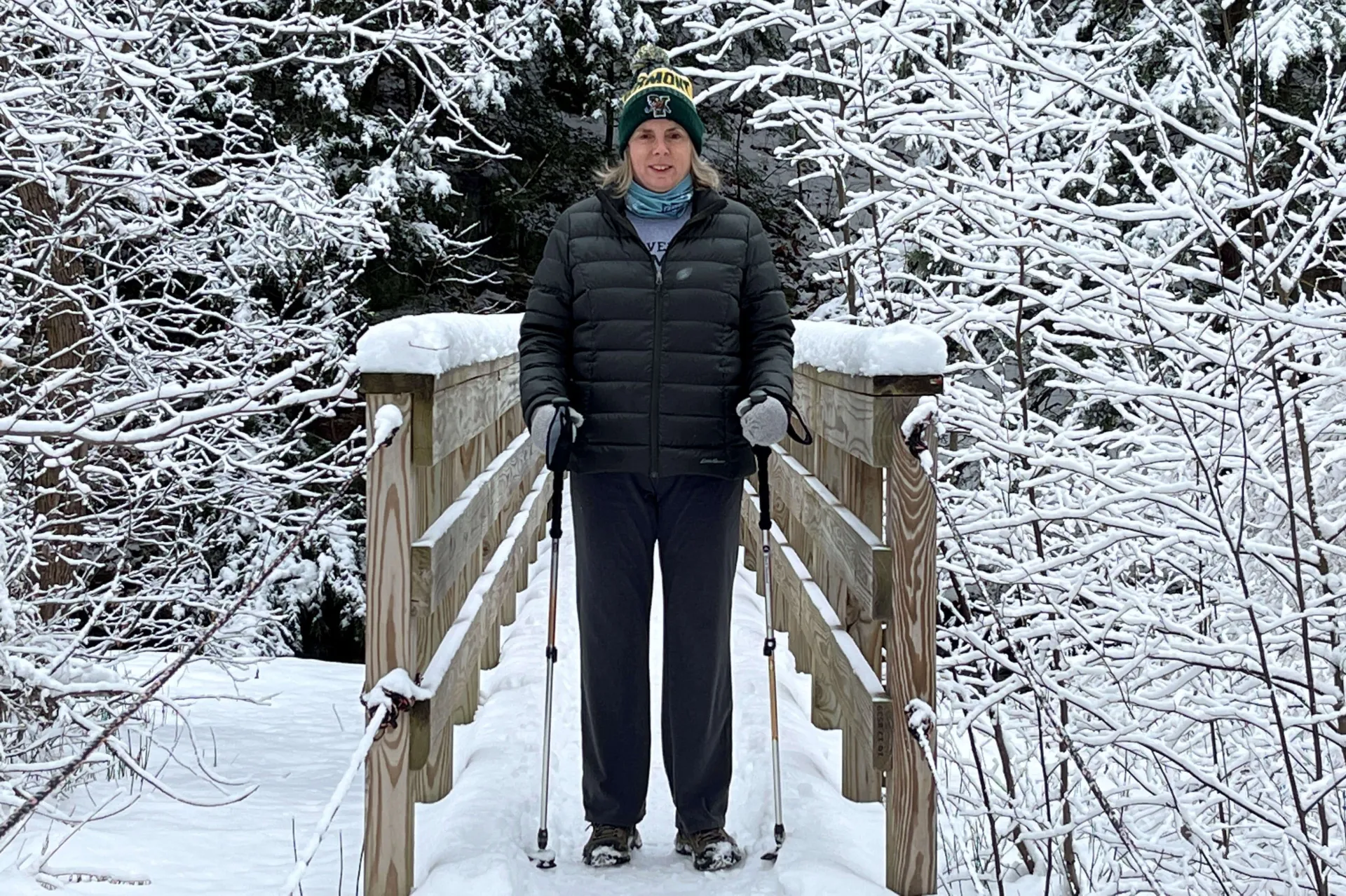 Corinne Thompson hikes across a snow covered bridge