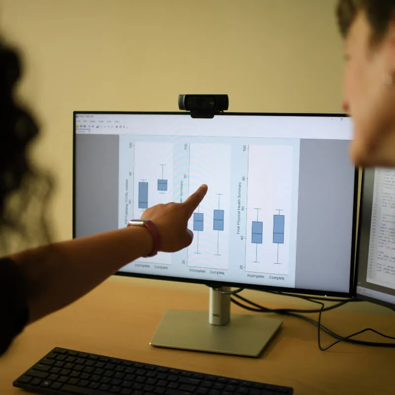 person showing someone a graph on a computer screen