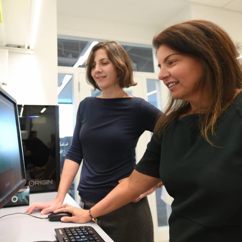 Two people look at a computer in a lab