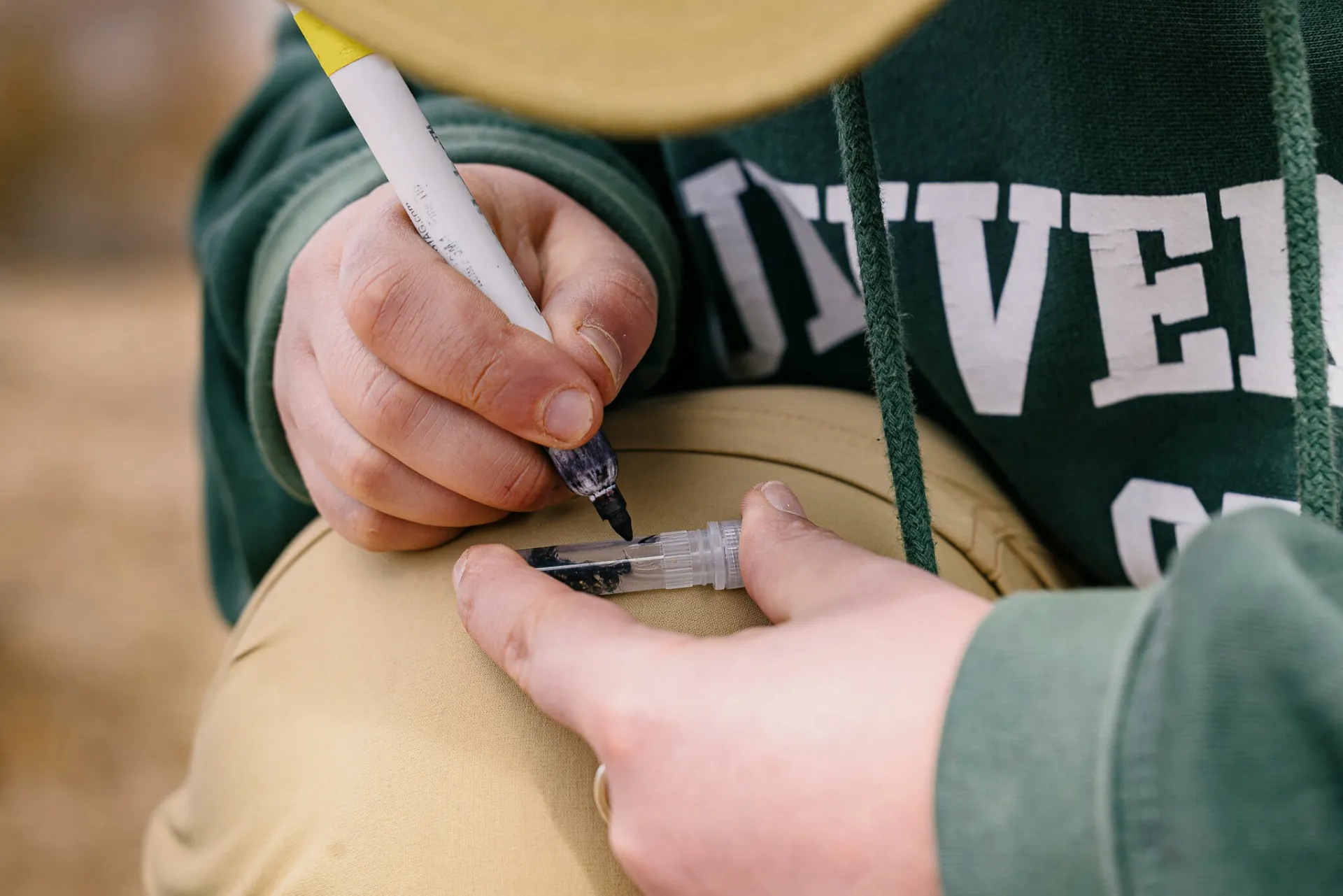 Sof Antello writes with a marker on a glass vial