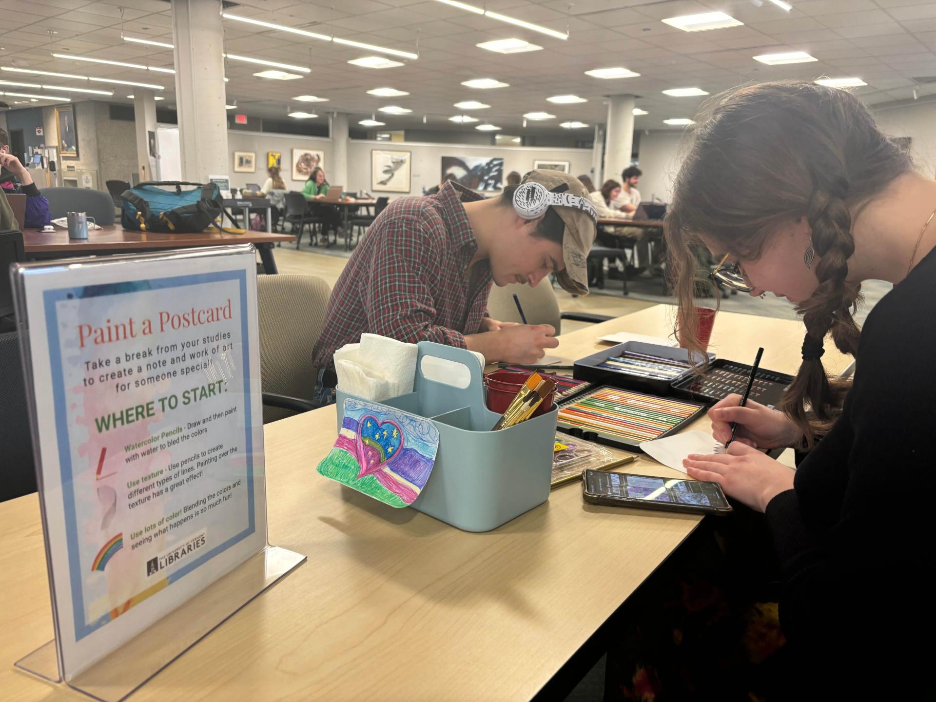 Students sitting at a table in Howe coloring with colored pencils.