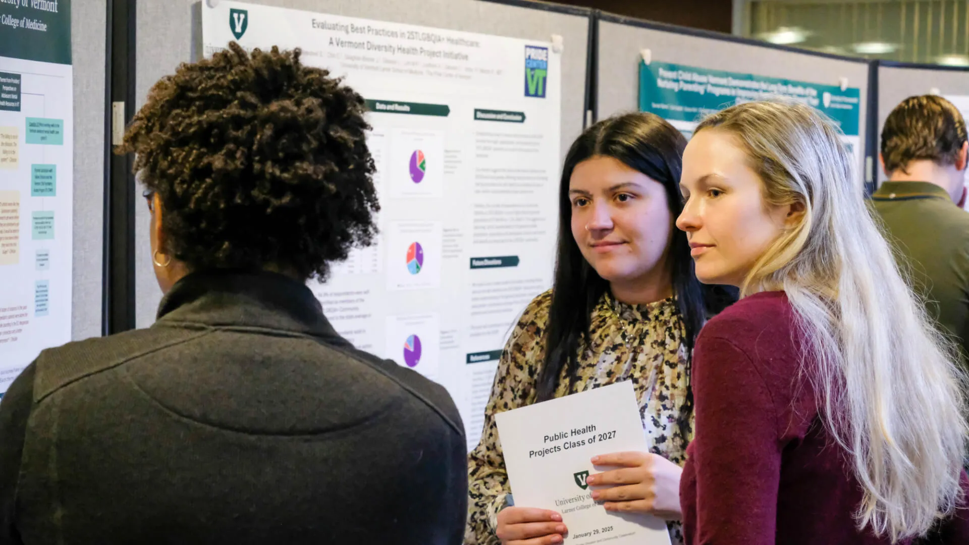 Three graduate students discuss a Public Health research poster