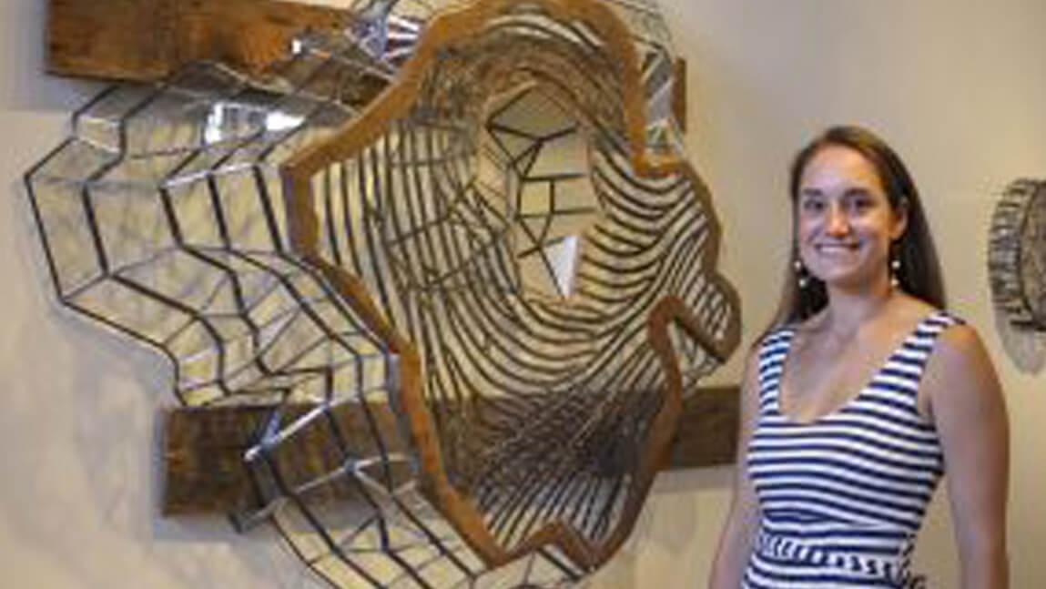 A person stands beside a large metal sculpture