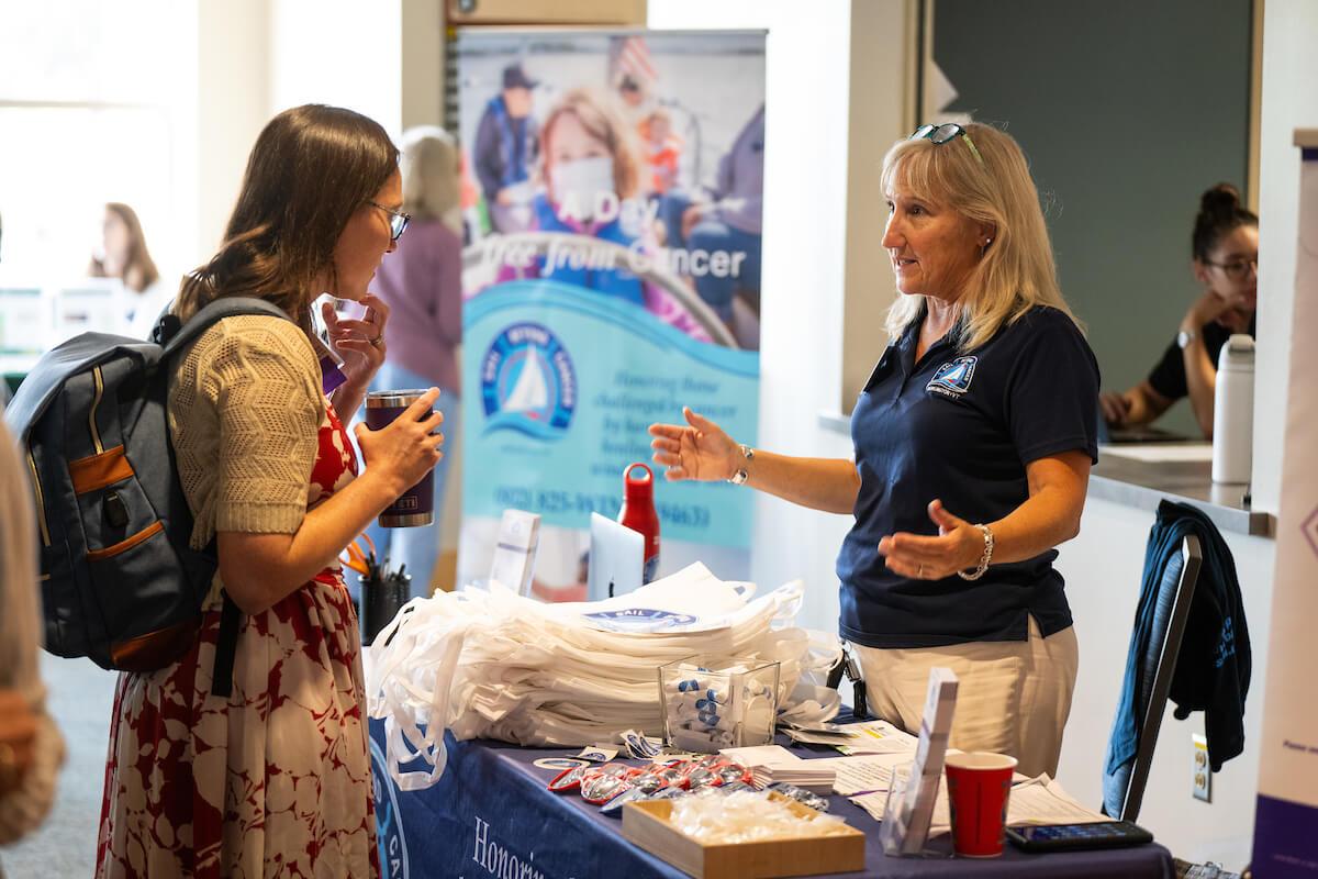Two people talking at an exhibitor booth at the Women's Health and Cancer Conference