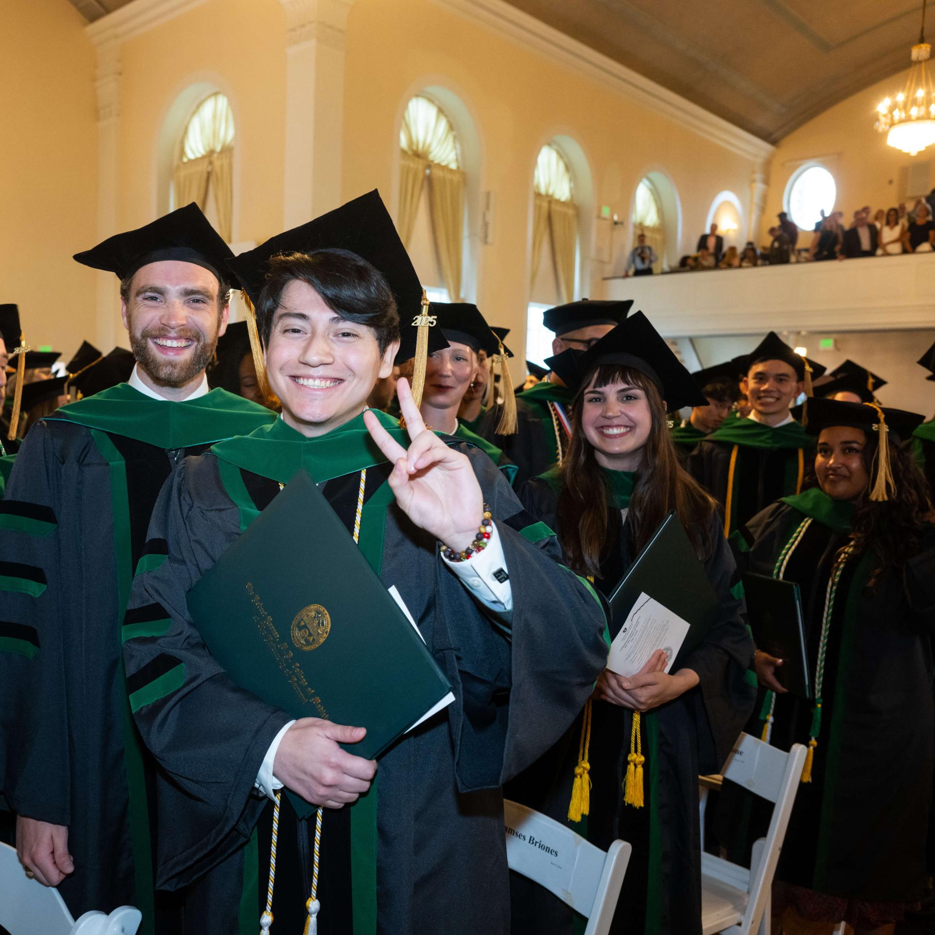 People standing in graduation robes, holding diplomas. 