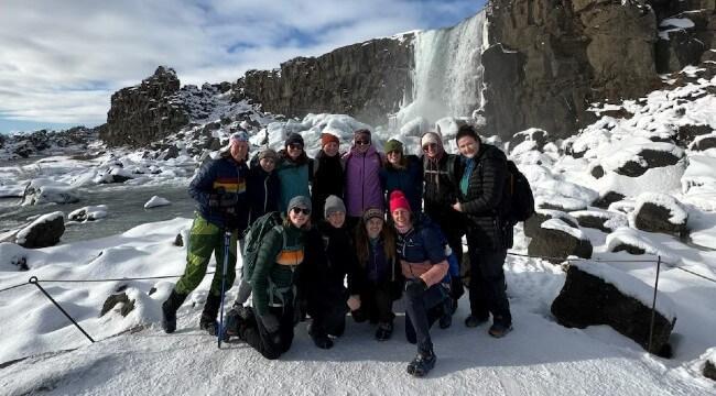 Students and faculty in front of snowy waterfall in Iceland