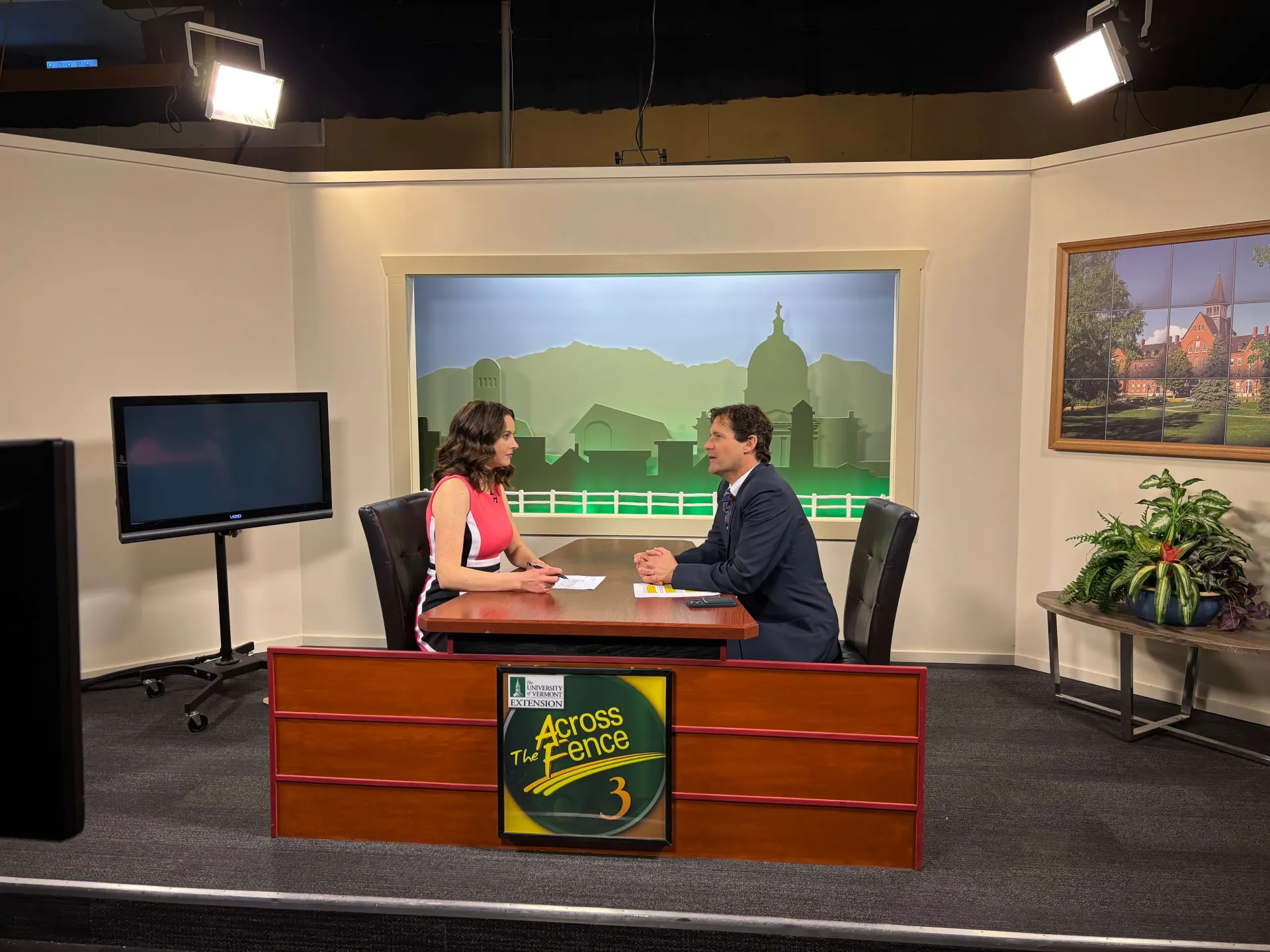 Two people sitting at a table in a news studio