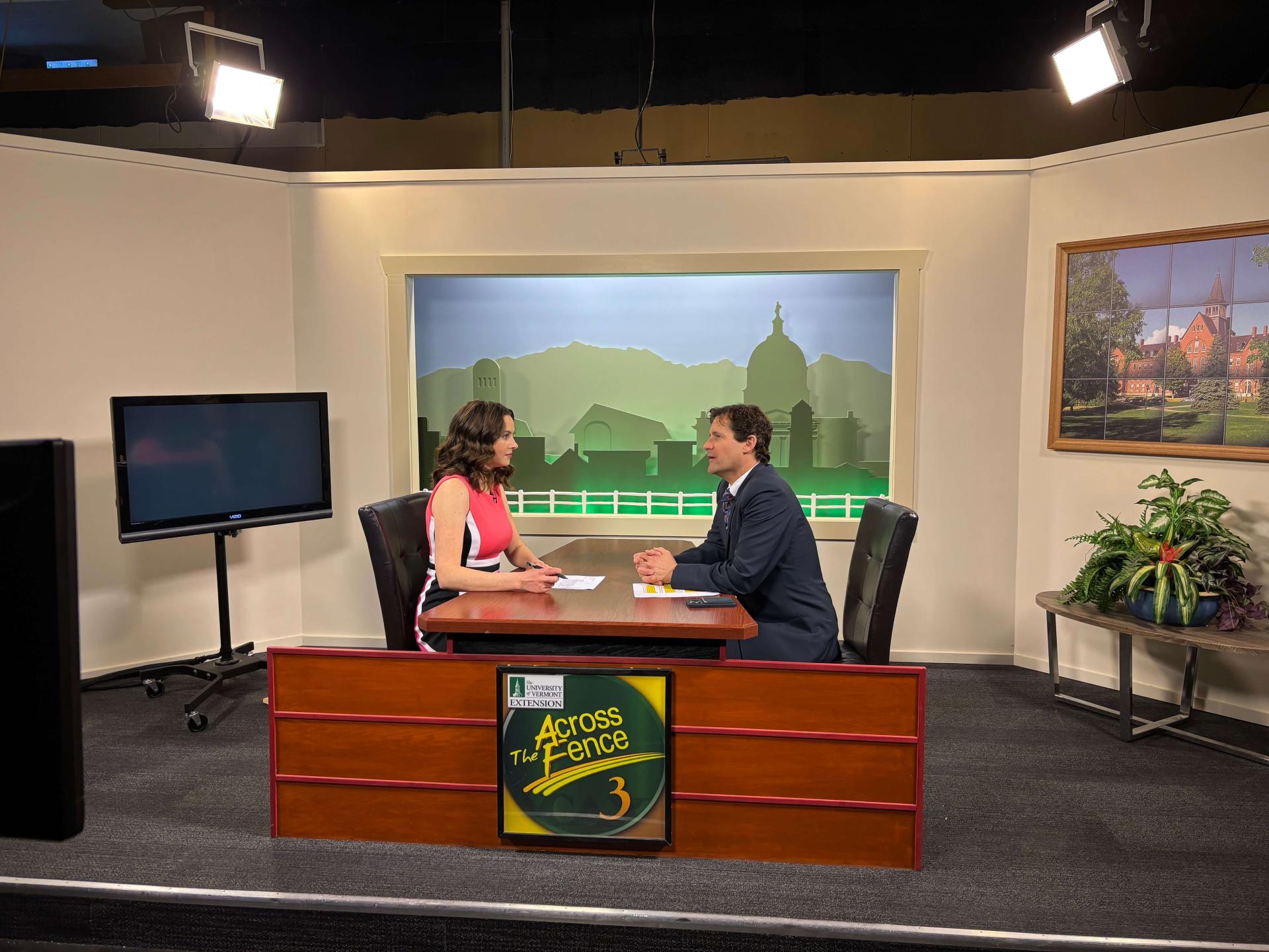 Two people sitting at a table in a news studio