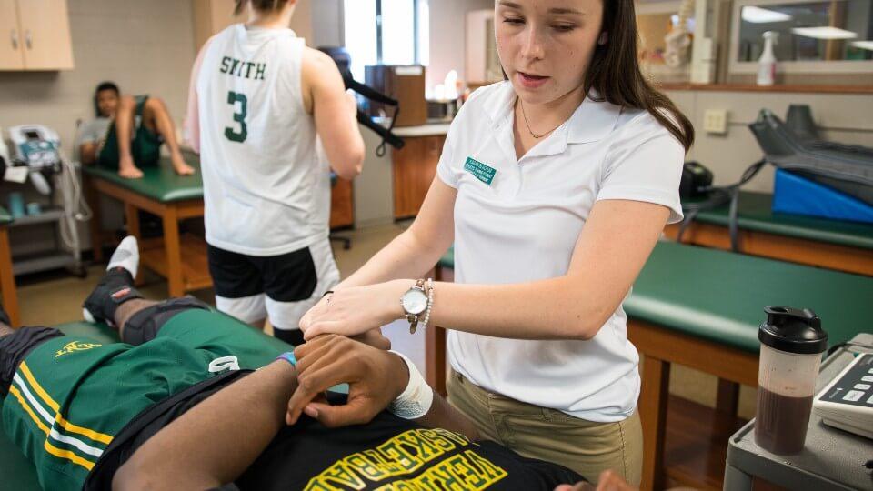 Athletic trainer working with athlete