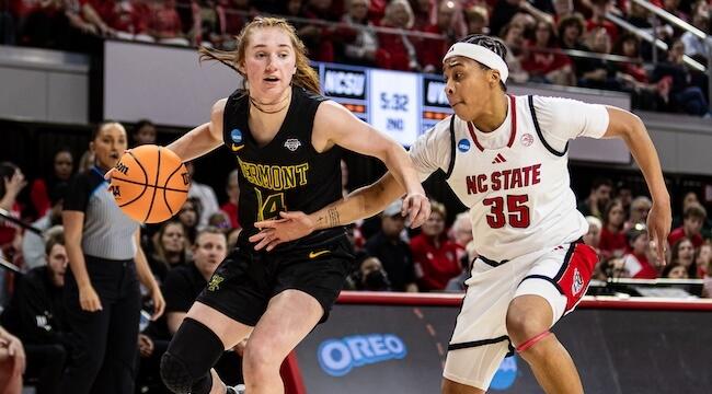 two women playing basketball, one driving, one defending