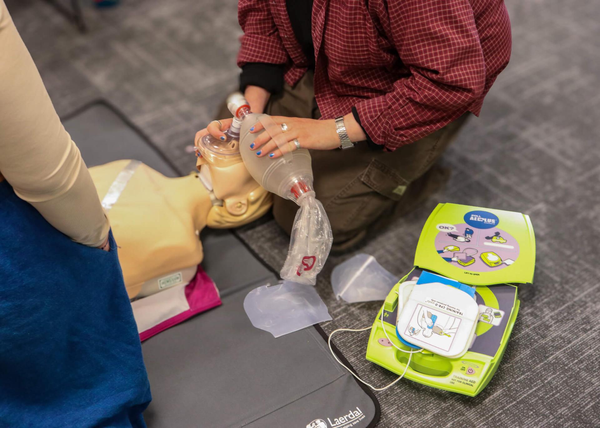 Students using a resuscitator bag and AED on a practice dummy.
