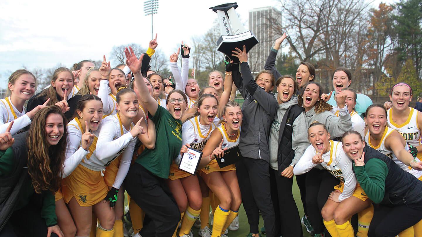 womens lacross team cheers while holding up a trophy