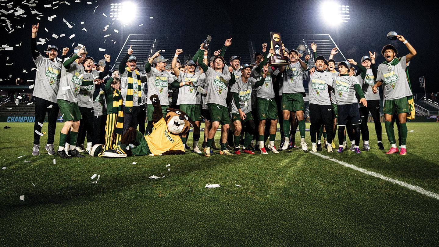 uvm mens soccer team cheering on a field with confetti after their win