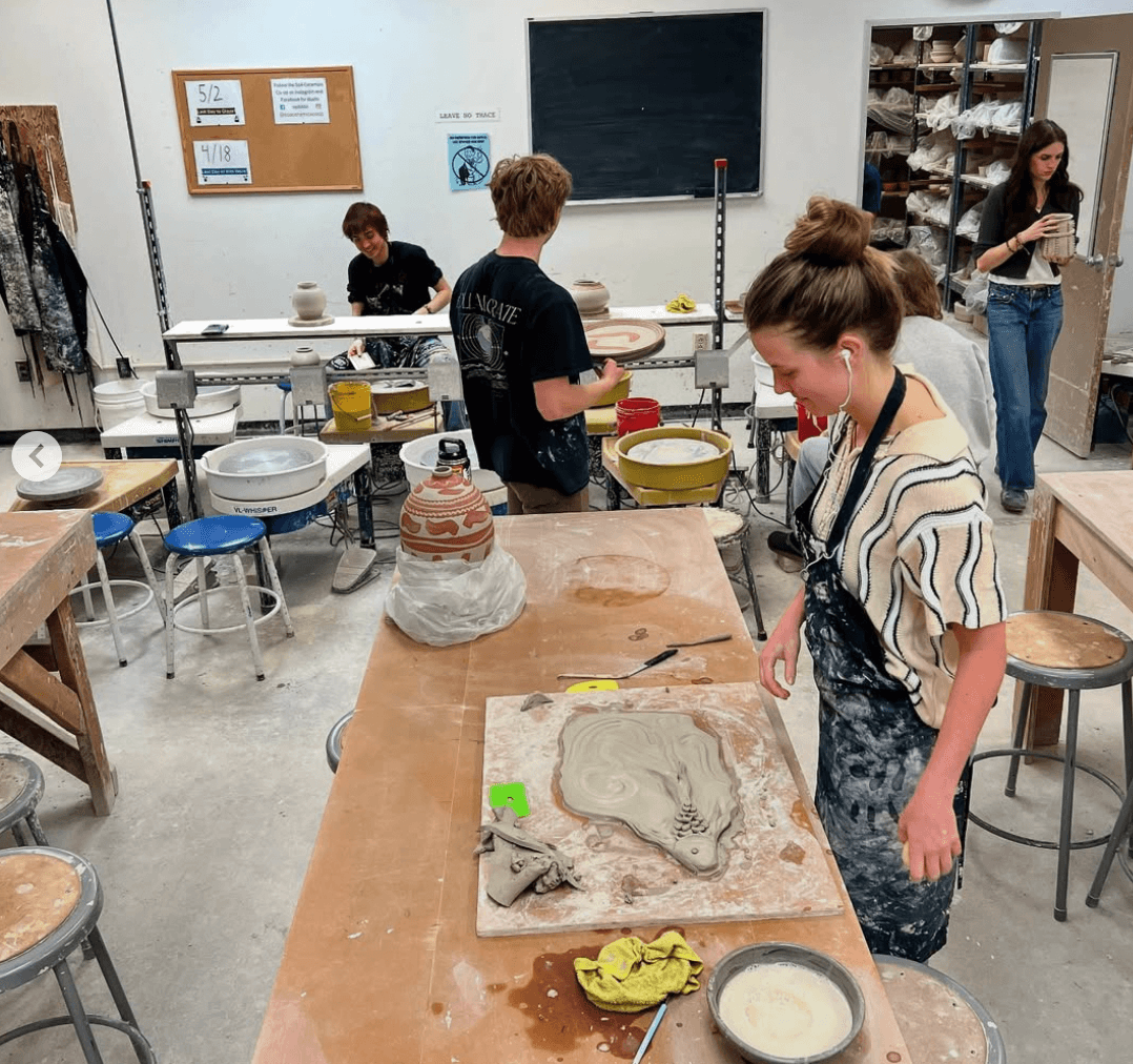  A group of students engaged in clay modeling in a well-lit studio