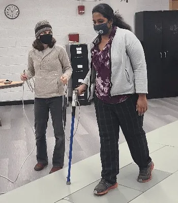 Two scientists demonstrating a walking assessment device.