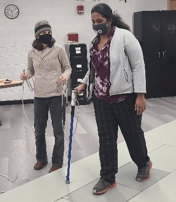 Two scientists demonstrating a walking assessment device.