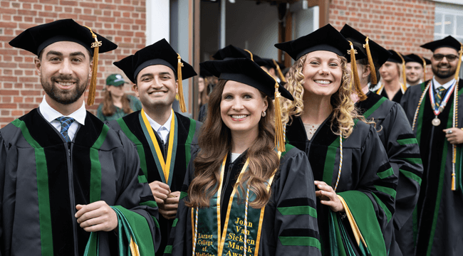Medical students in UVM regalia smiling as they line up to graduate