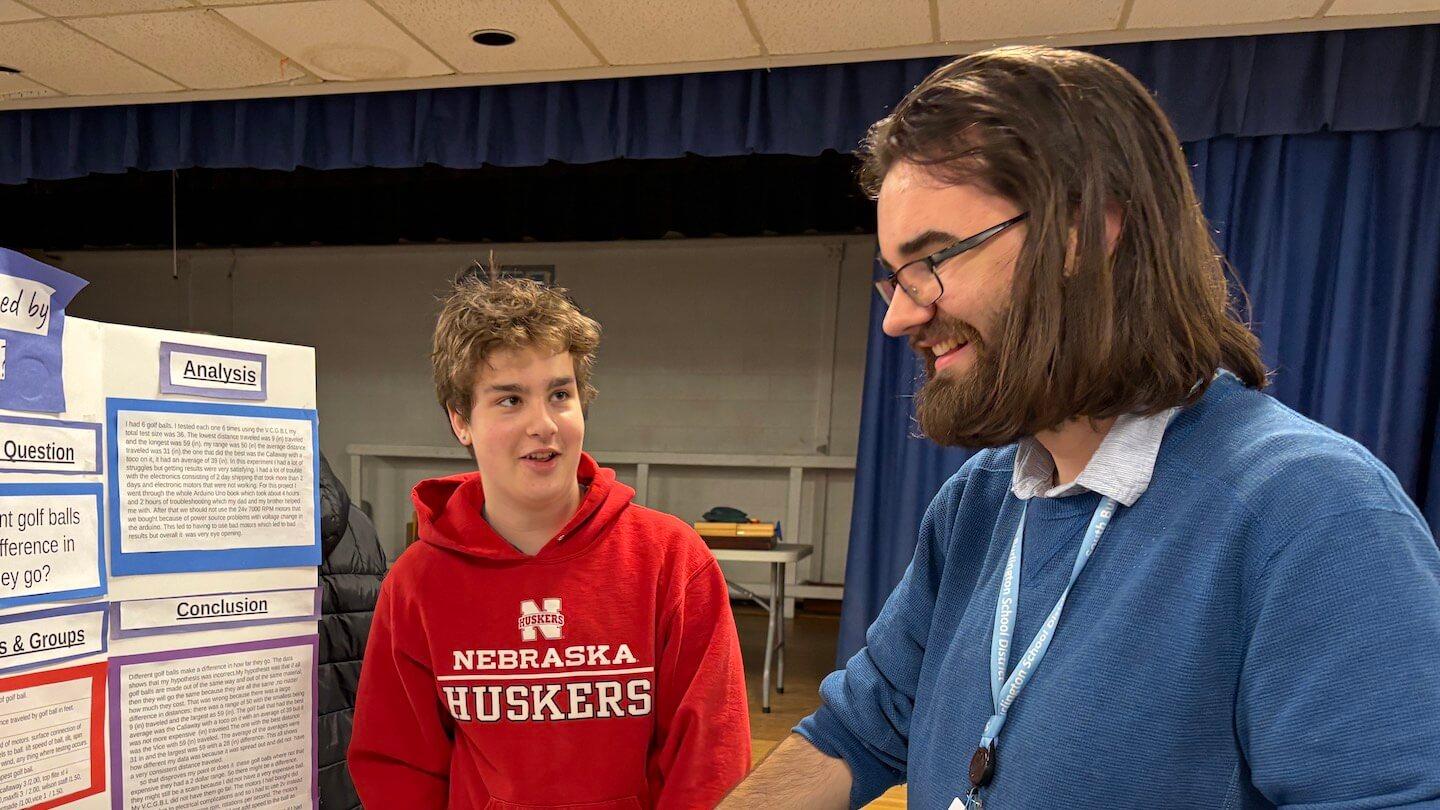 Kevin Columbo engages with a student at a science fair.