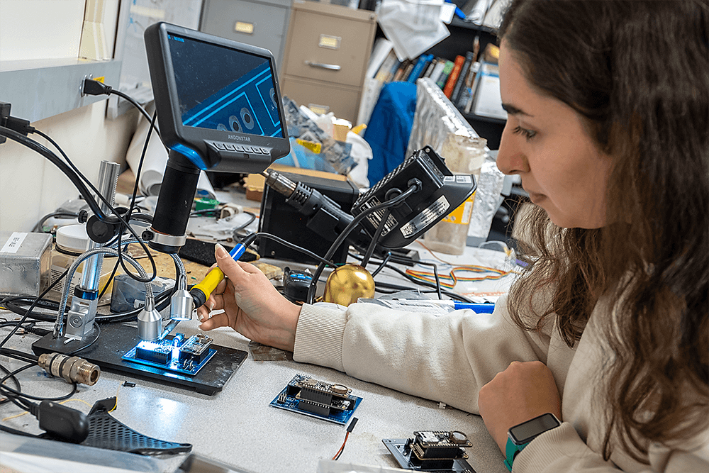 A graduate student in the Electrical and Computer Engineering Program builds a circuit board in Dr. Tian Xia's lab