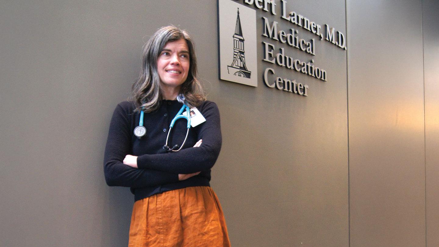 a woman leans against a wall with a sign that says robert larner md medical education center