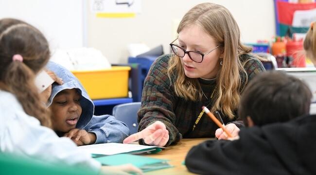 student teacher with yound students at a table