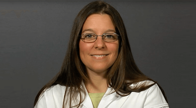 a woman in a white coat smiling