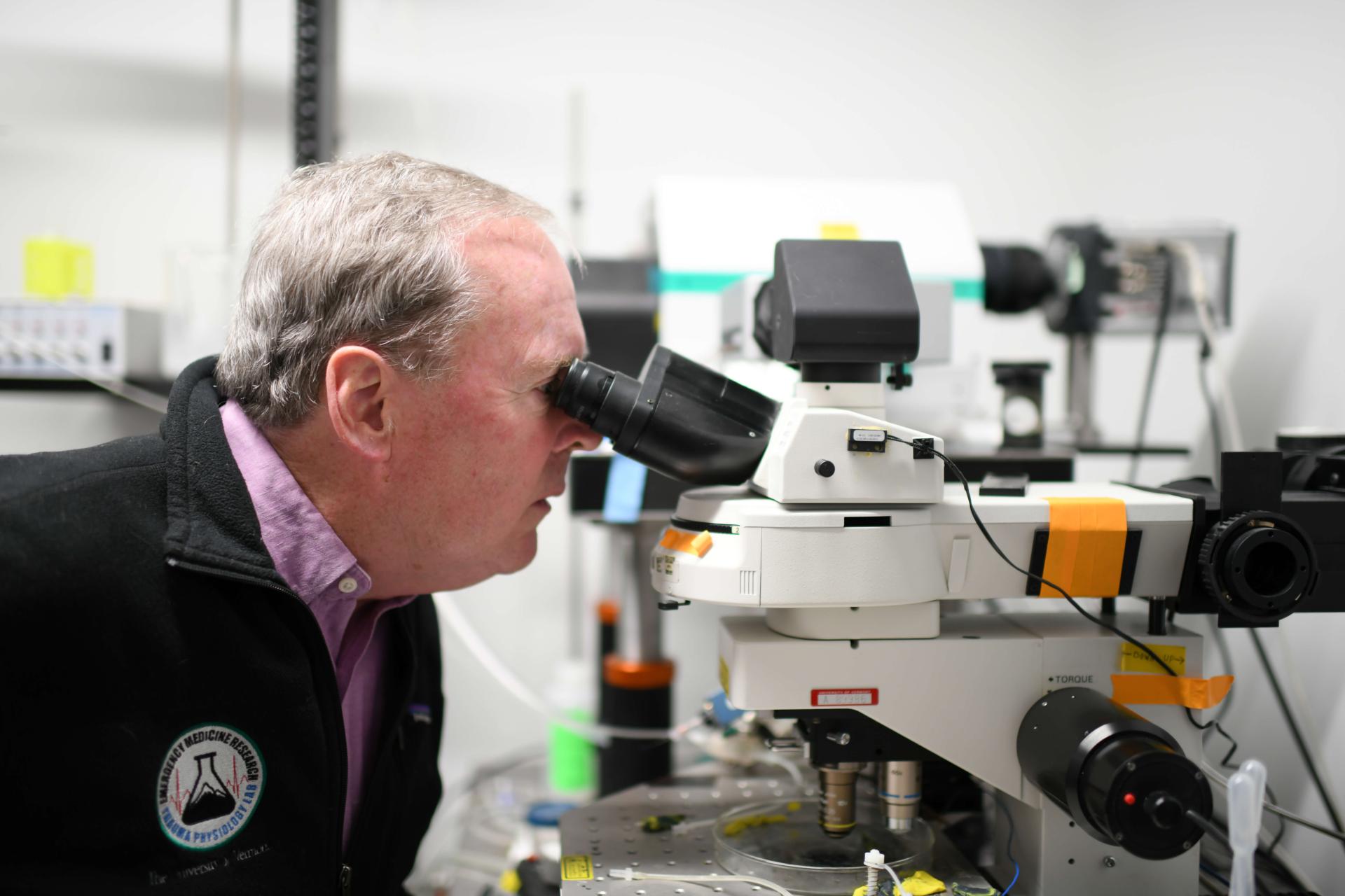 Person looking in a microscope in a lab 