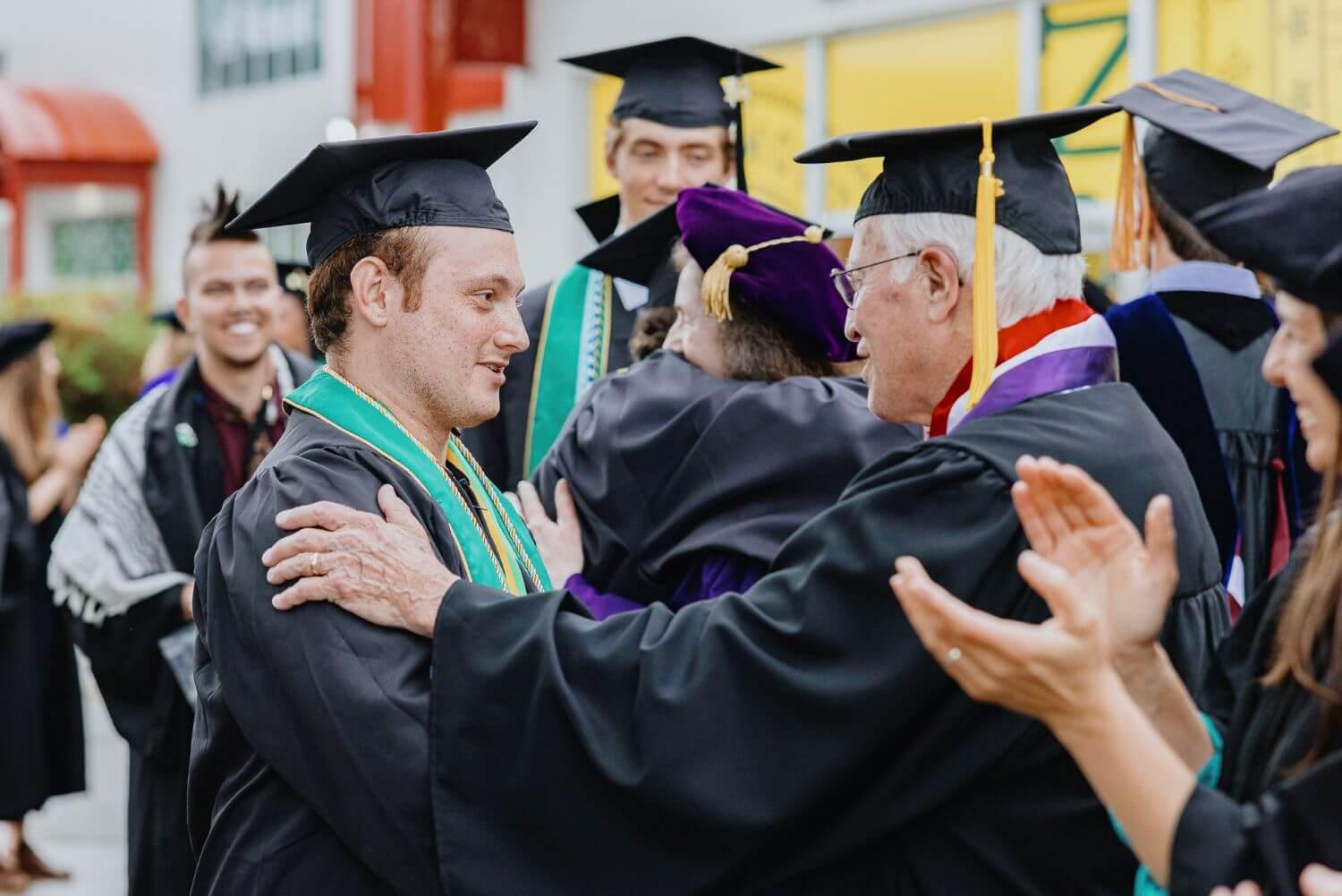 RSENR students in the recessional greeting and hugging faculty