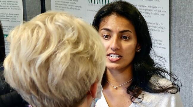 young woman speaking to a person in front of research poster