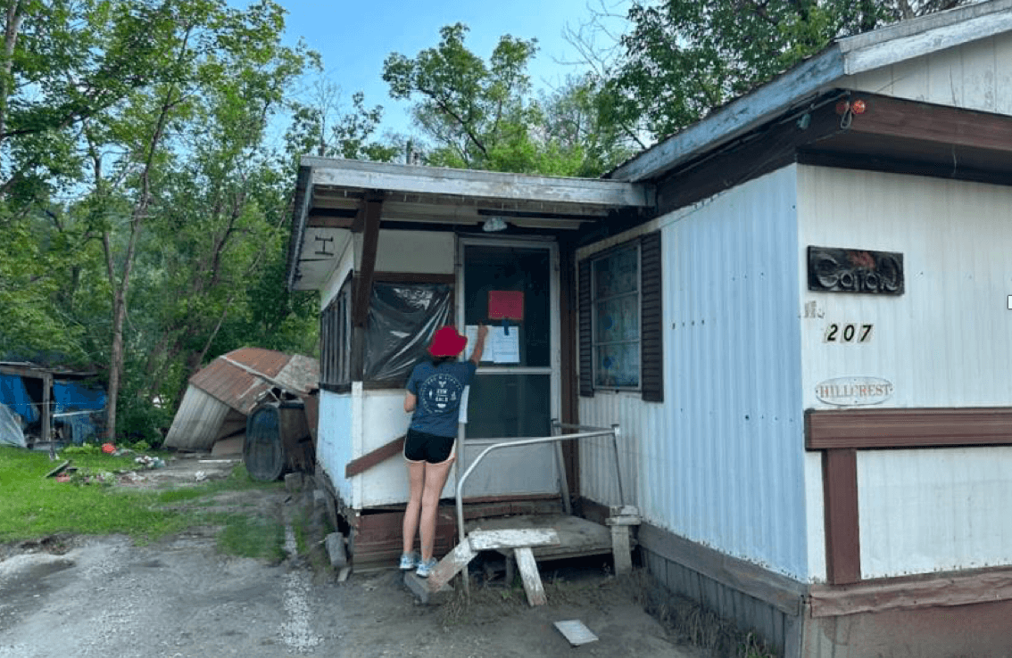 student knocking on doors of a mobile home park