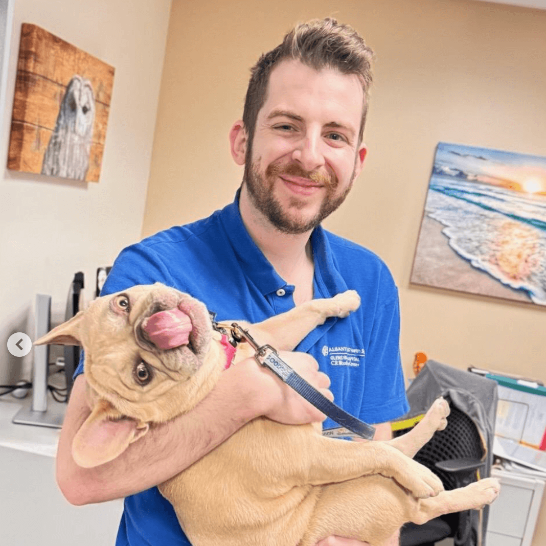 Ted smiling at the camera holding his dog.