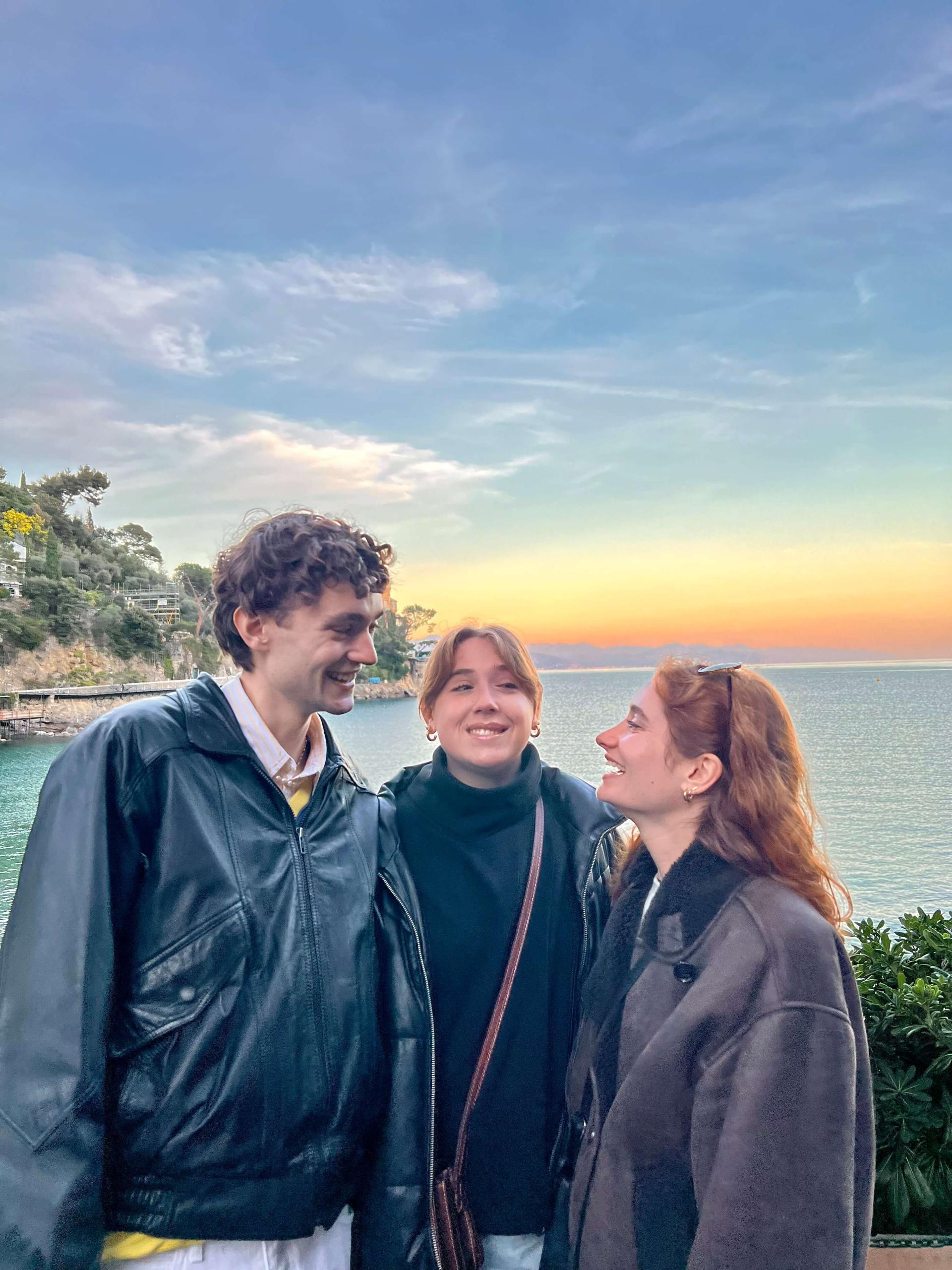 Chloe (right) and her friends in Italy posing for a photo by the ocean at sunset.