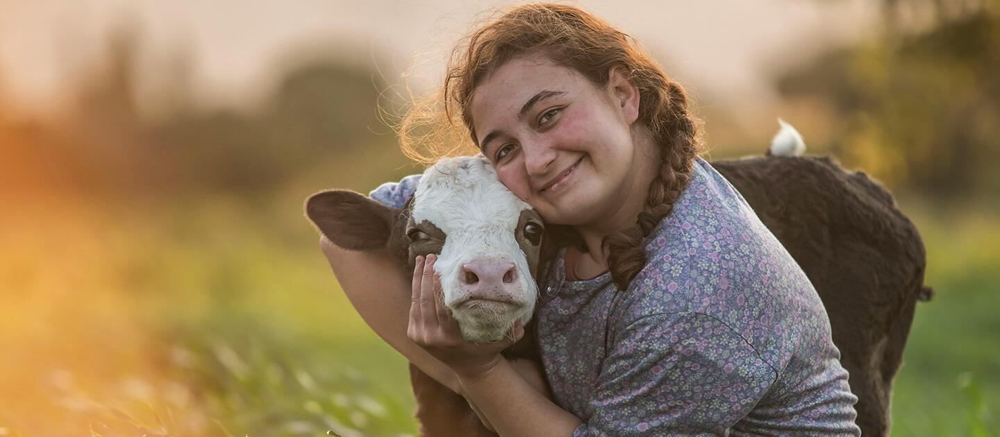 young lady hugging a young cow