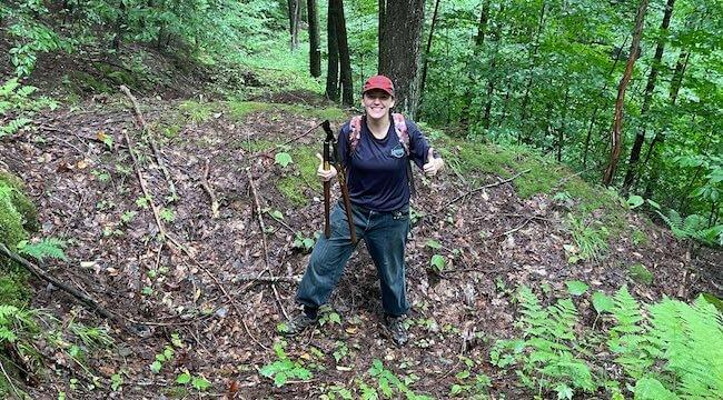 person standing on leaf-strewn forest floor