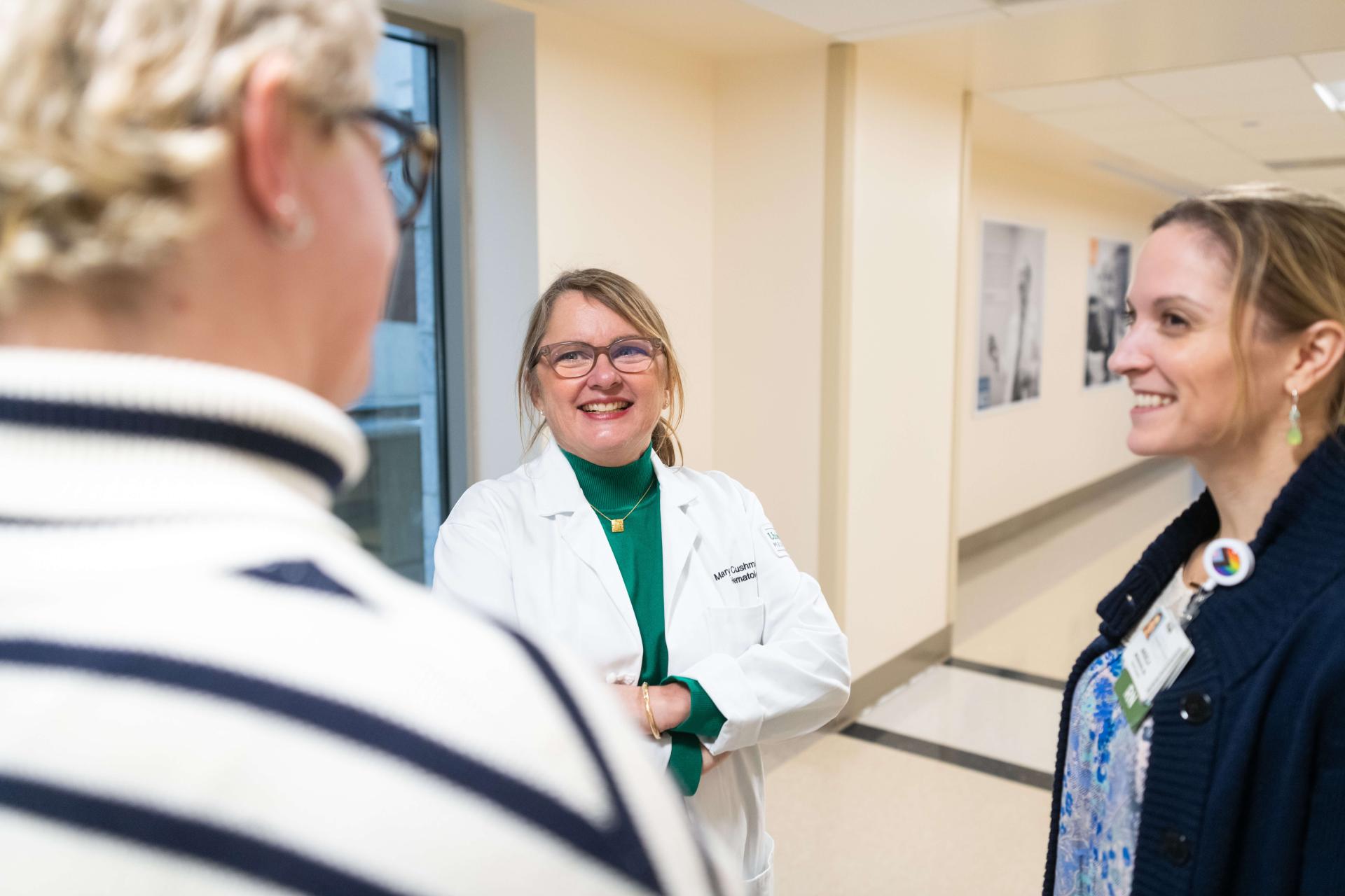 3 People standing together in conversation in a hallway