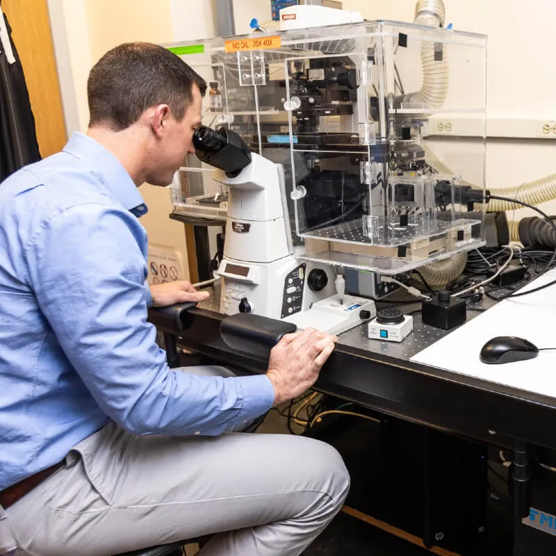man looking into a complex looking microscope