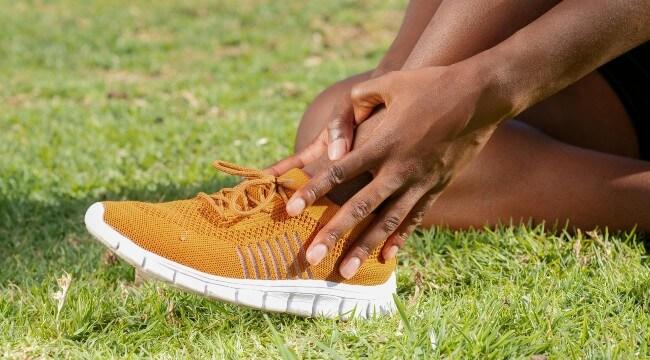 Student athletes lower leg with hands holding ankle
