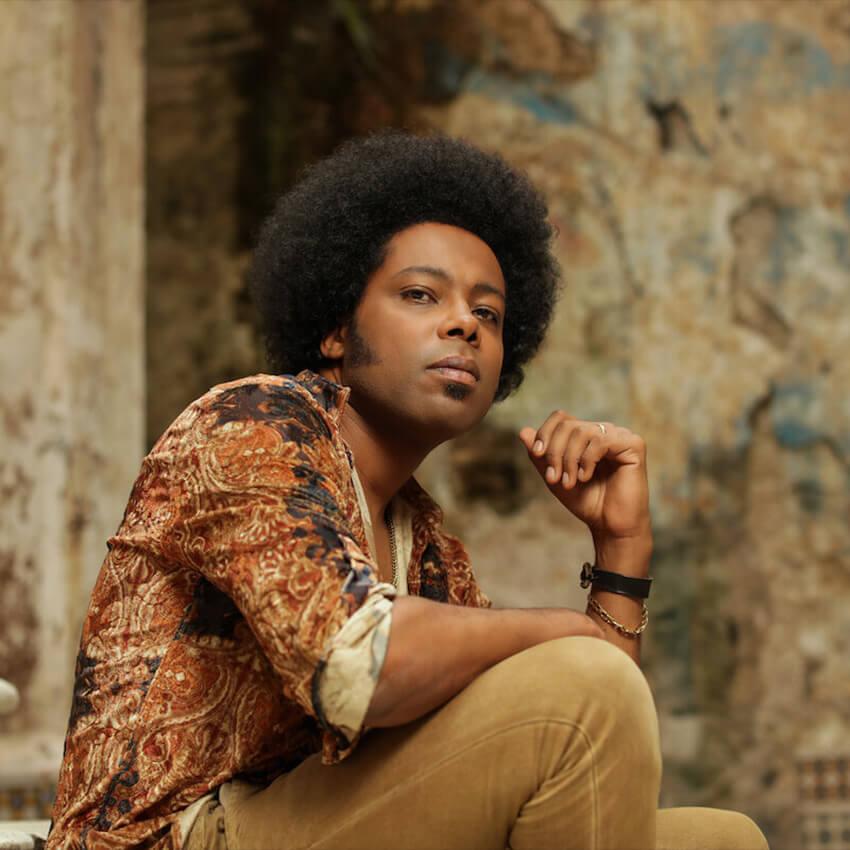 Alex Cuba sits on stoop looking at us over his right shoulder.