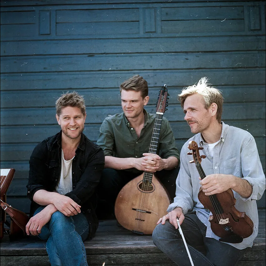Dreamers' Circus sitting in front of a blue walk with their instruments.