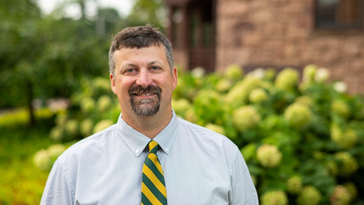 Dave Blatchly smiling outside wearing a green and yellow tie