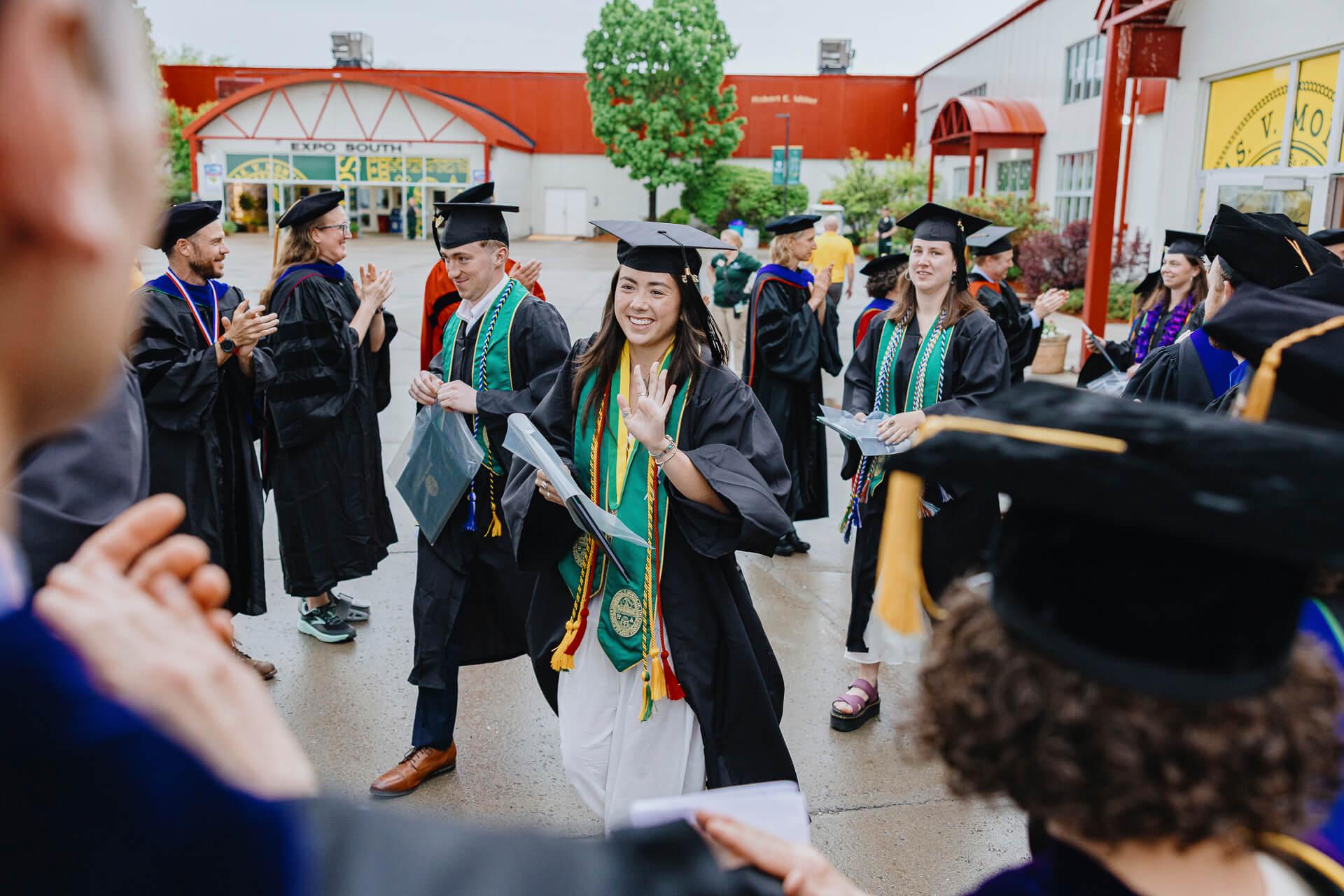 Dexter holding her diploma waving at her professors.