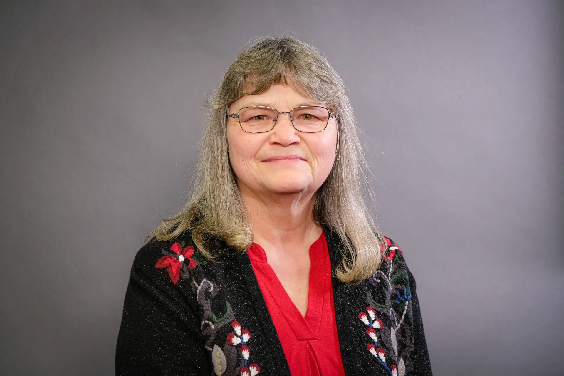 Margaret Doyle in a red blouse under a black sweater with flower details. 