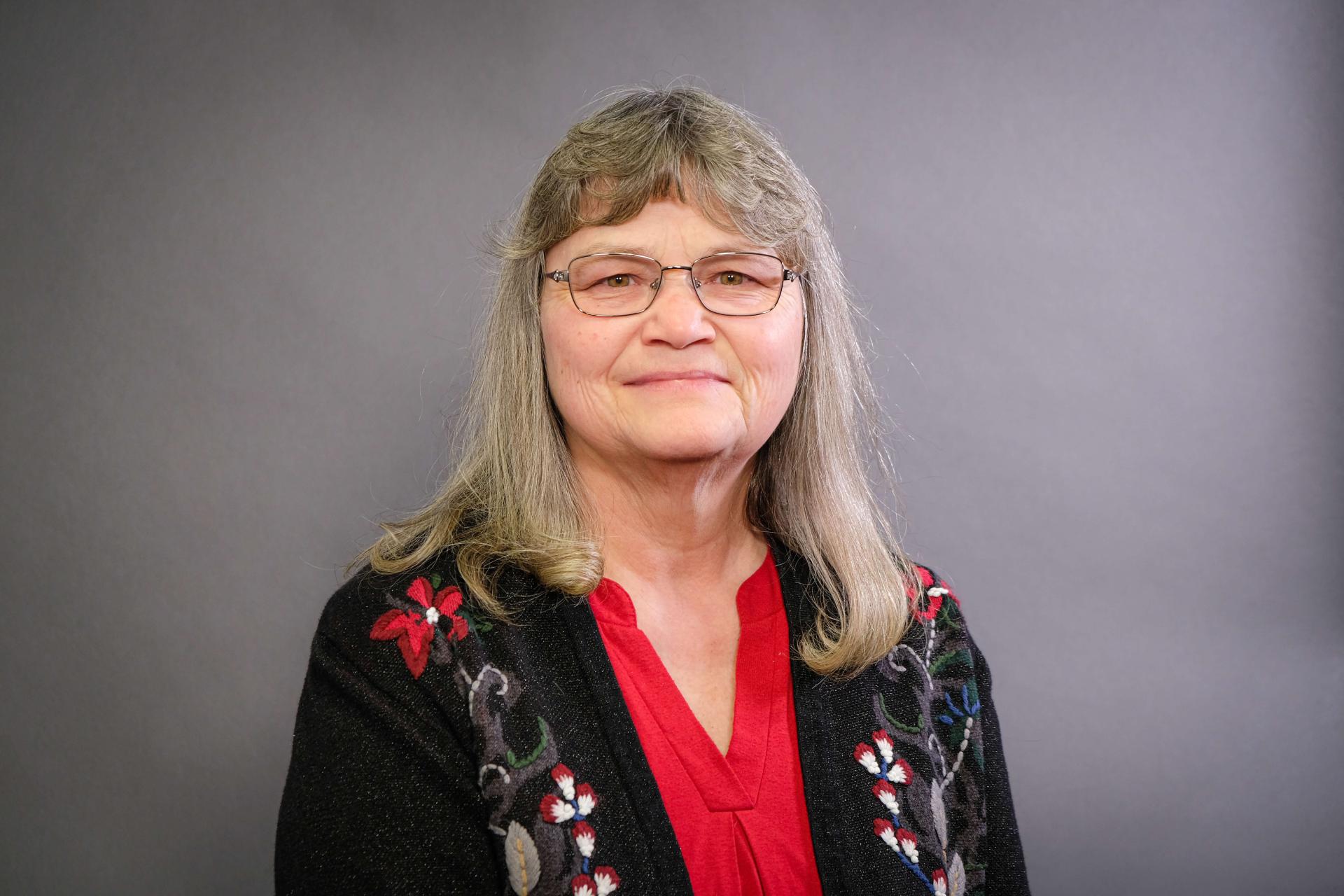 Margaret Doyle in a red blouse under a black sweater with flower details. 