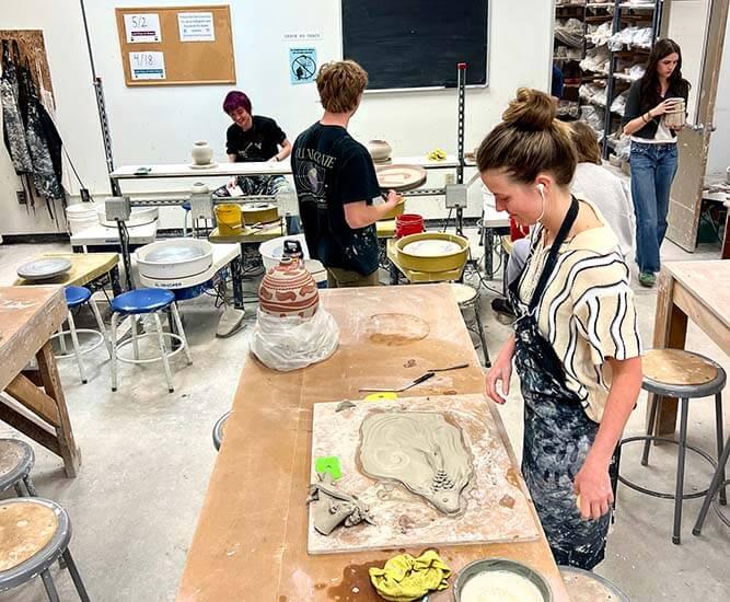  A group of students engaged in clay modeling in a well-lit studio